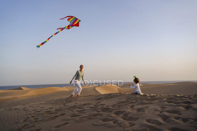 Mother and daughter flying kite in sand dunes, Gran Canaria, Spain — Stock Photo