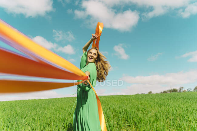Щаслива молода жінка в зеленій сукні в полі зі стрічками — стокове фото