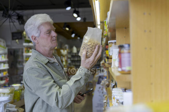 Uomo anziano che compra generi alimentari in un piccolo negozio di alimentari — Foto stock