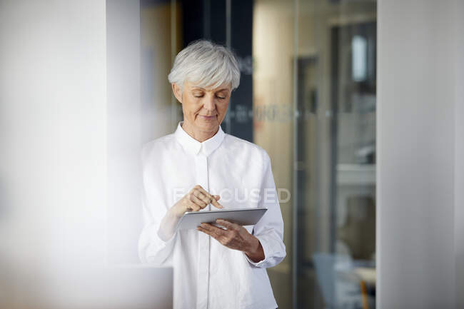 Retrato de la mujer de negocios senior usando tableta digital en la oficina - foto de stock