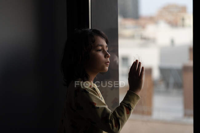 Boy looking out of window at home — Stock Photo