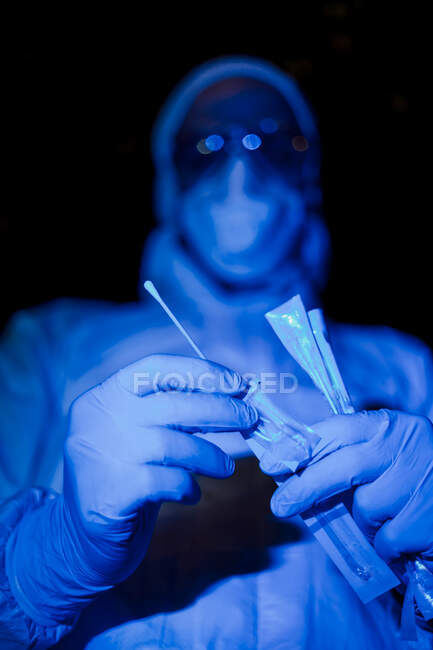 Médecin portant des vêtements de protection, tenant un test de prélèvement viral — Photo de stock