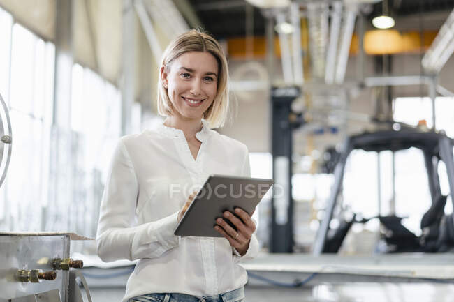 Ritratto di giovane donna sorridente che utilizza tablet in una fabbrica — Foto stock