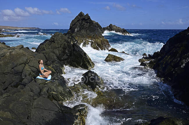 Femme méditant à la piscine naturelle, Parc National Ariagara, Aruba, Antilles — Photo de stock