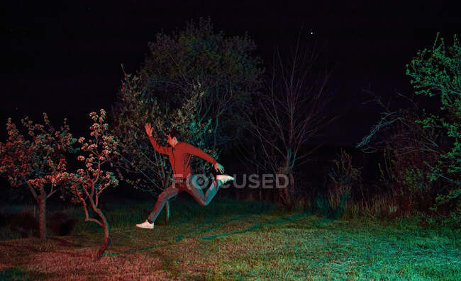 Мужчина прыгает в сад ночью — стоковое фото