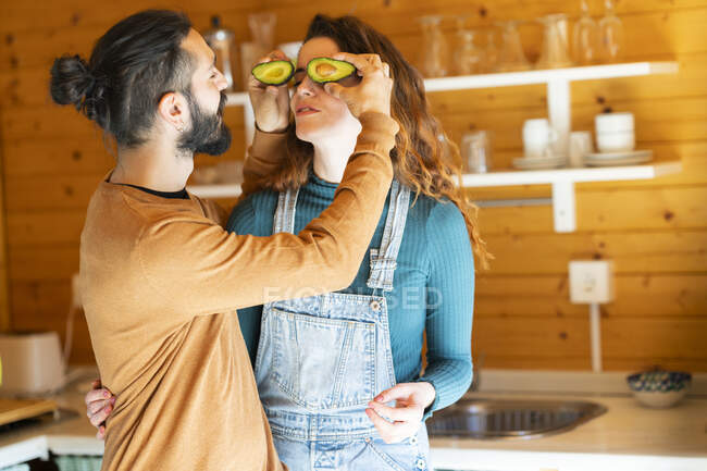 Verspieltes junges Paar vergnügt sich mit Avocados in Holzhütte — Stockfoto