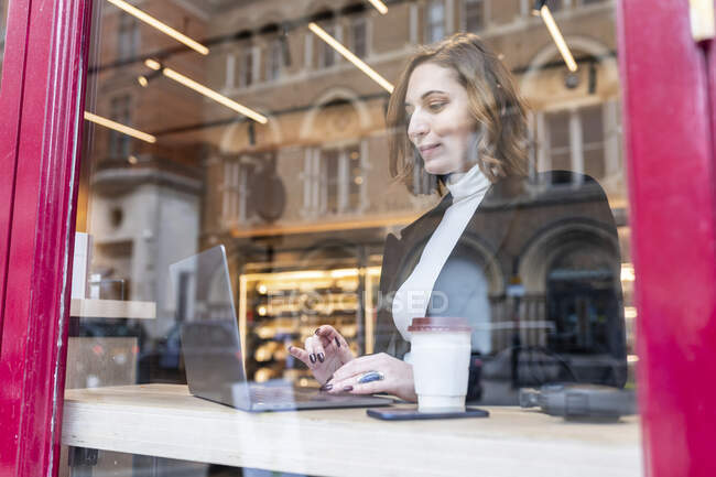 Empresária usando laptop em um café na cidade — Fotografia de Stock