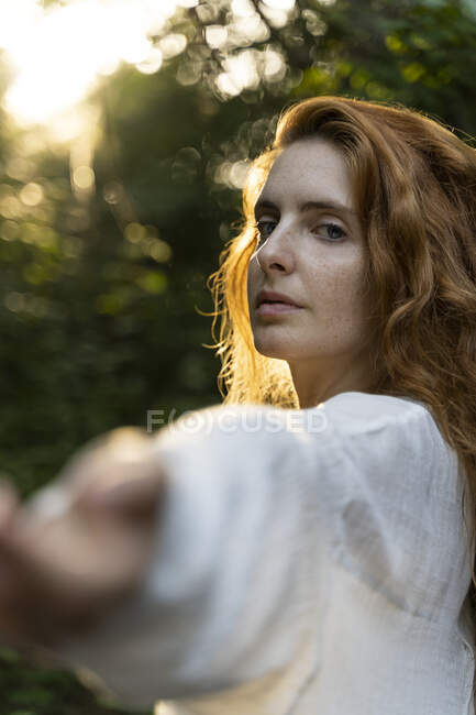 Jeune femme rousse étendant les mains dans la forêt — Photo de stock