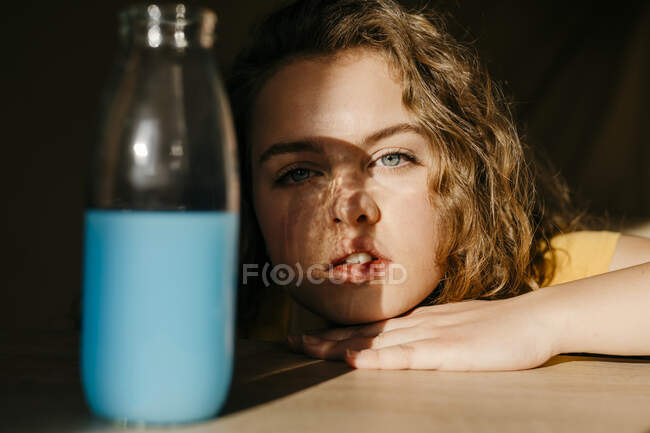 Ritratto di giovane donna bionda a casa con bottiglia colorata — Foto stock