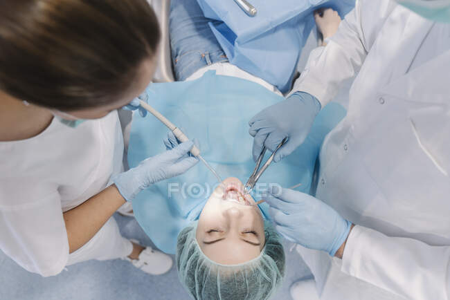 Mujer joven recibiendo tratamiento dental en la clínica - foto de stock