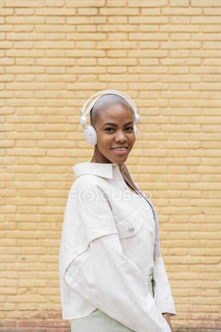 Ritratto di donna sorridente che ascolta musica con cuffie all'aperto — Foto stock