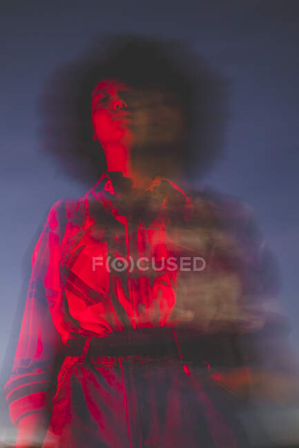 Mujer joven borrosa con peinado afro al aire libre por la noche - foto de stock