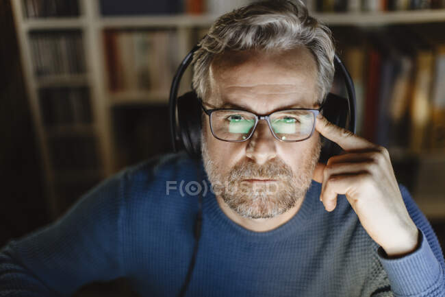 Porträt eines nachdenklichen reifen Mannes mit Kopfhörern vor dem Computer — Stockfoto