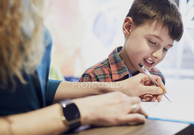 Madre compilando il modulo per suo figlio presso lo studio medico — Foto stock