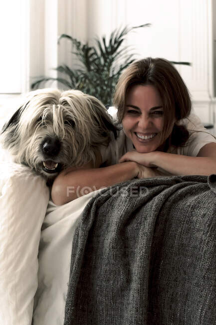 Ritratto di donna matura che ride sdraiata sul letto con il suo cane — Foto stock