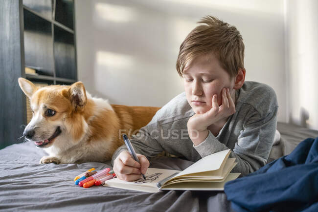 Retrato del dibujante acostado en la cama con su perro - foto de stock