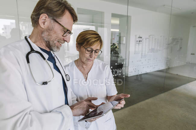 Doctor and assistant using tablet in medical practice — Stock Photo
