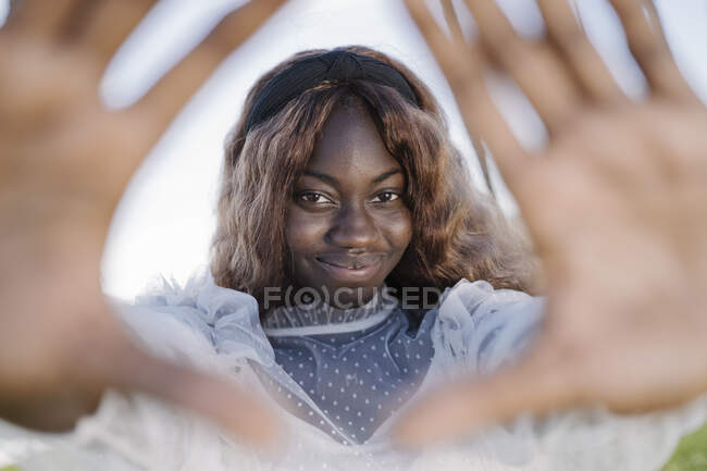 Portrait of smiling teenage girl making a hand frame outdoors — Stock Photo