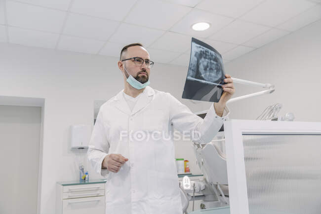 Denist steht in Zahnklinik und betrachtet Röntgenbild — Stockfoto