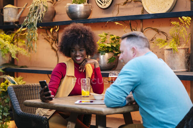 Чоловік і жінка п'ють у ресторані, використовуючи смартфон. — стокове фото
