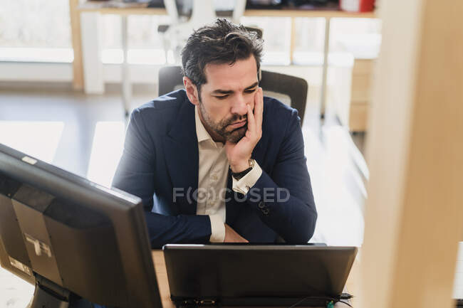 Frustrierter Geschäftsmann sitzt im Büro am Schreibtisch — Stockfoto