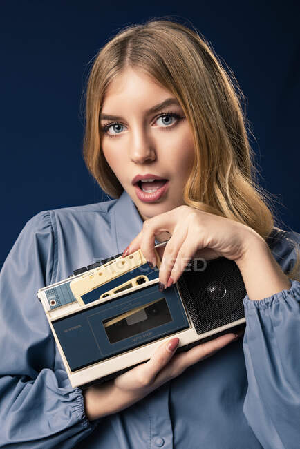 Femme blonde avec lecteur de cassette devant fond bleu — Photo de stock