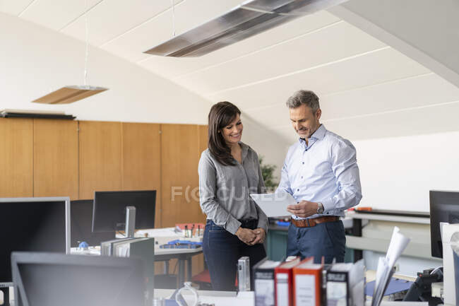 Бізнесмен і бізнесменка обговорюють папір в офісі. — стокове фото