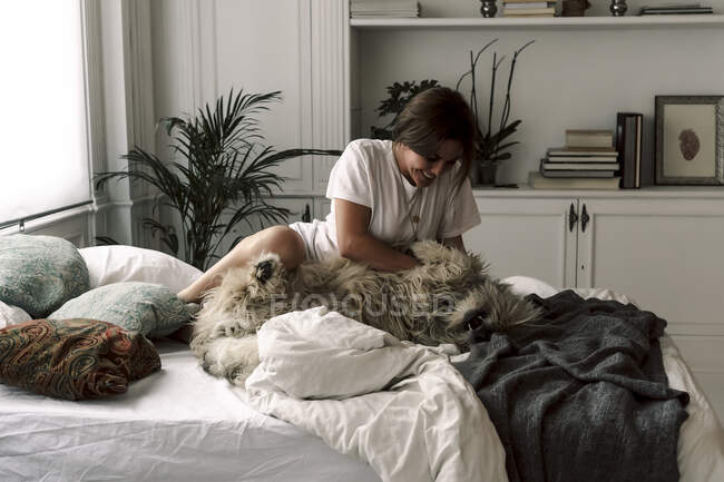 Mature woman cuddling her dog on bed — Stock Photo