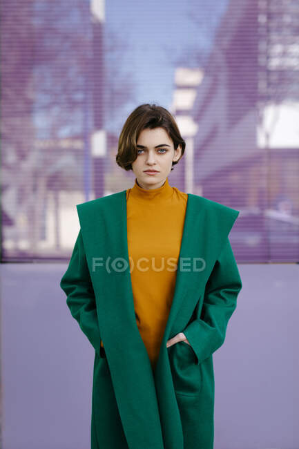 Jovem mulher vestindo casaco verde na frente de uma vidraça — Fotografia de Stock