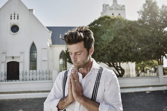 Retrato de homem em roupas antiquadas no campo rezando em uma igreja — Fotografia de Stock