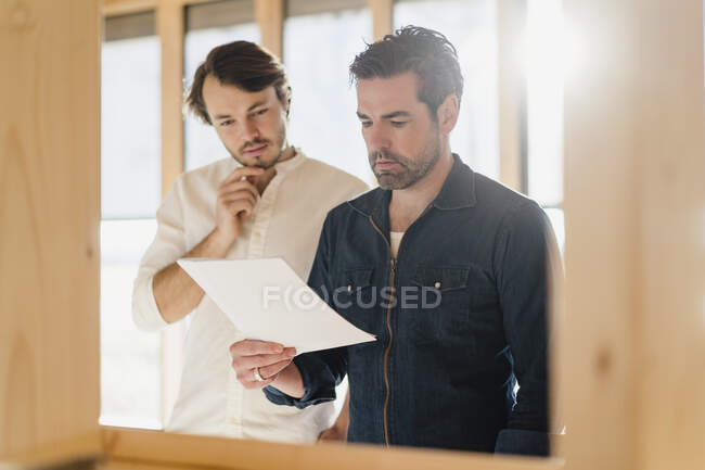 Due uomini d'affari con documento in ufficio open space di legno — Foto stock