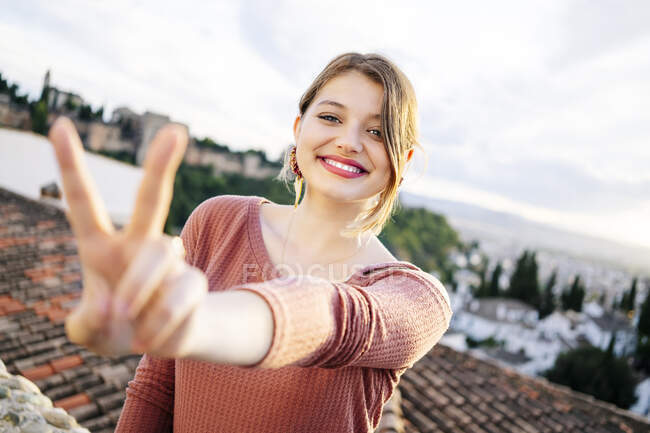 Портрет счастливой женщины, делающей победный жест с Альгамброй на заднем плане, Гранада, Испания — стоковое фото