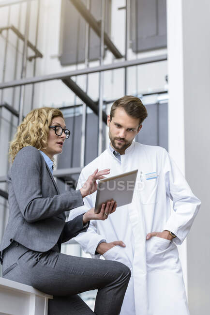 Femme d'affaires avec comprimé et médecin parlant à l'hôpital — Photo de stock