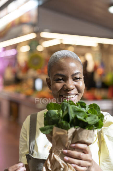 Portrait of happy woman holding paper bag in a market hall — Stock Photo