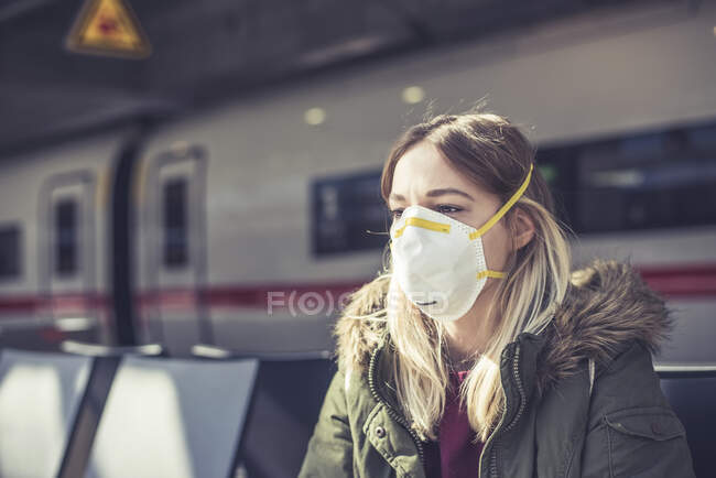 Retrato de una mujer joven con máscara respiratoria en la plataforma de la estación - foto de stock