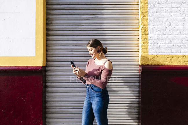 Mujer feliz usando smartphone en un edificio de la ciudad - foto de stock