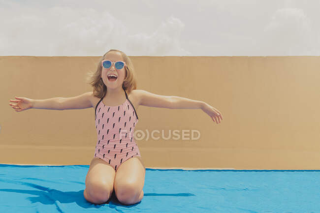 Portrait of happy girl wearing pink sunglasses and swimsuit having fun on roof terrace — Stock Photo