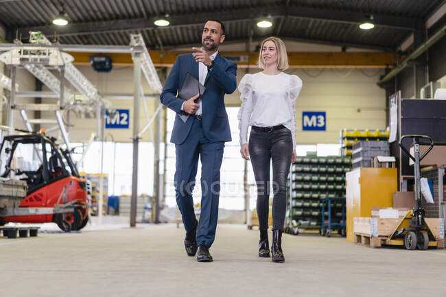 Бизнесмен и молодая женщина ходят и разговаривают на фабрике — стоковое фото
