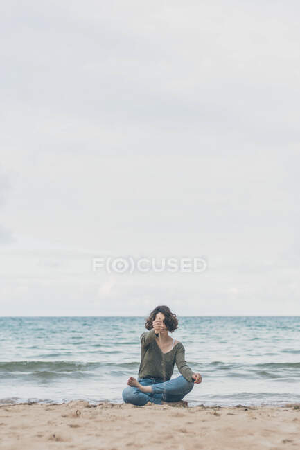 Jovem mulher sentada na praia, com areia escorrendo pelas mãos — Fotografia de Stock
