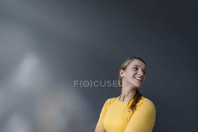 Retrato de una joven feliz en una pared gris - foto de stock