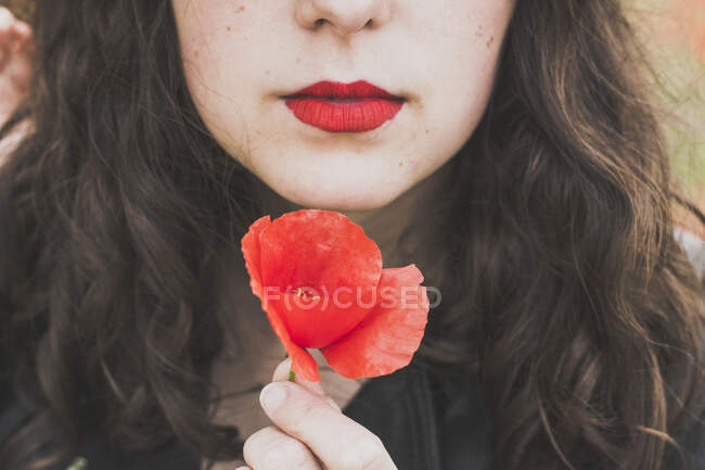 Vue de la récolte de la jeune femme avec des lèvres rouges tenant le pavot — Photo de stock