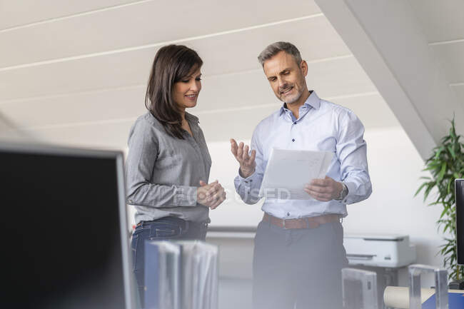 Businessman and businesswoman discussing paper in office — Stock Photo