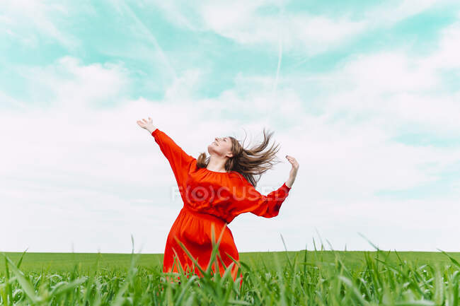 Щаслива жінка в червоній сукні танцює в полі — стокове фото