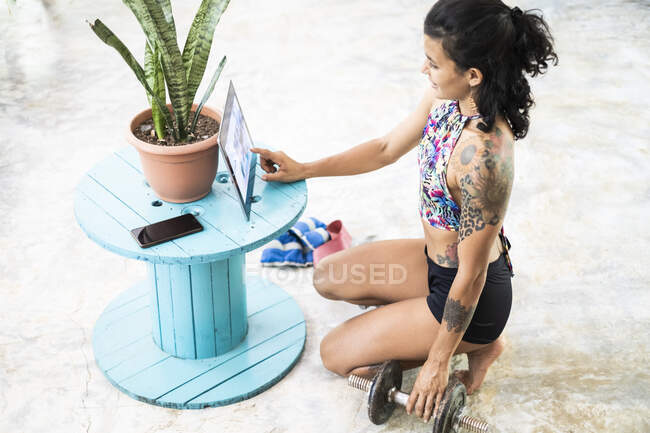 Young woman using tablet during workout at home — Stock Photo