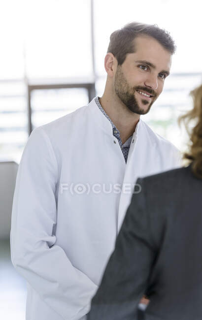 Retrato del médico confiado teniendo una reunión con una mujer de negocios en el hospital - foto de stock