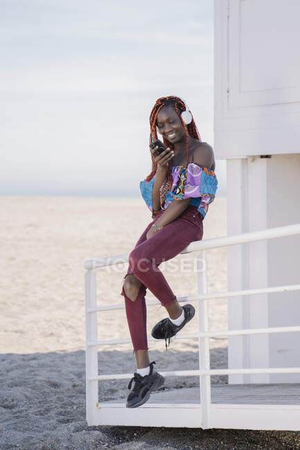 Усміхнена дівчина-підліток з навушниками та смартфоном на пляжі — стокове фото
