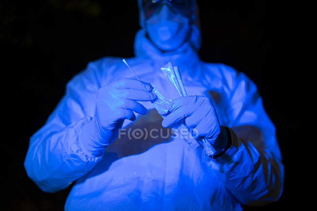 Médico vestindo roupas protetoras, segurando teste de swab viral — Fotografia de Stock