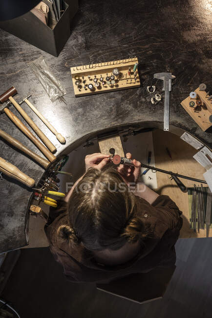 Female goldsmith working with grinder on silver ring, from above — Stock Photo