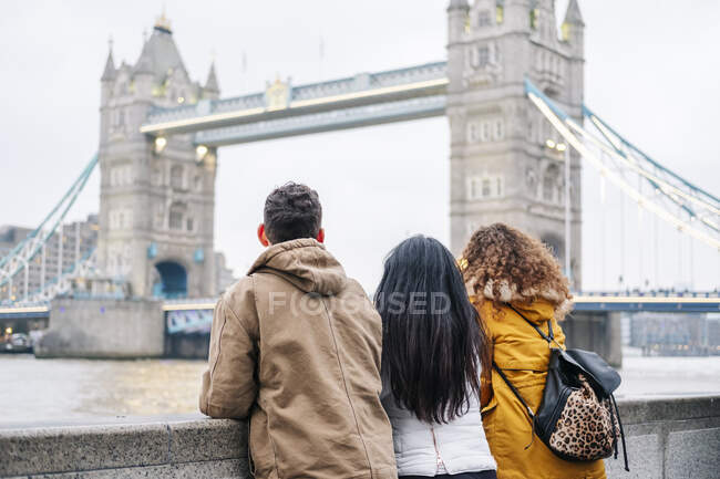 Jóvenes turistas mirando el Puente de Londres, vista trasera - foto de stock