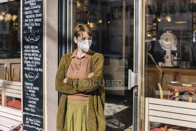 Woman wearing mask standing in front of her closed restaurant — Stock Photo